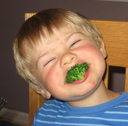 Toddler with veggie in mouth