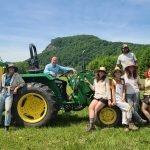 UMass students and Adam Hession of Big Y on a tractor on a field.